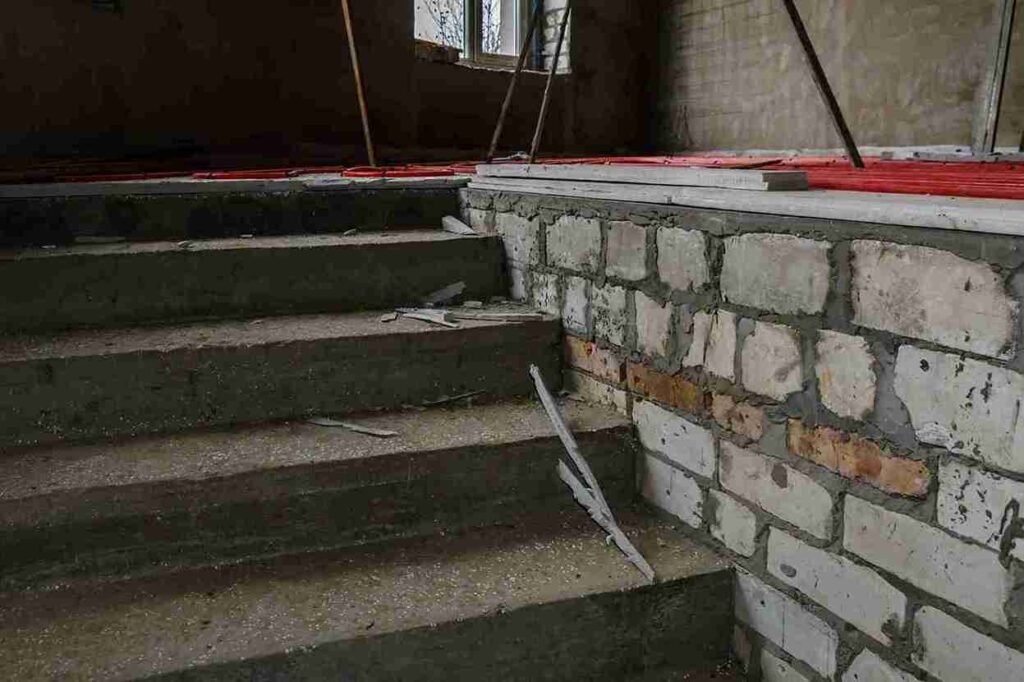 Concrete stairs under renovation with exposed stone wall in a Brunswick OH property.