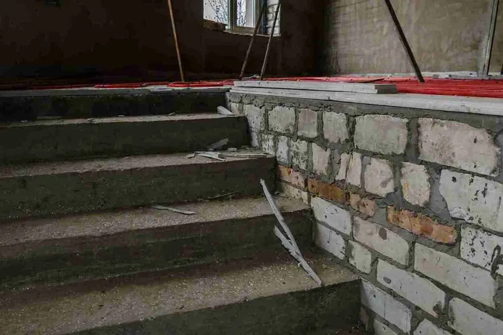Concrete stairs under renovation with exposed stone wall in a Brunswick OH property.